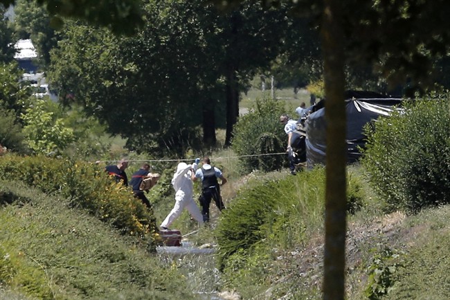 Investigating police officers work outside the plant where an attack took place, Friday, June 26, 2015 in Saint-Quentin-Fallavier, southeast of Lyon, France. French authorities say one person has been beheaded in an attack and explosion at a gas factory in the southeastern part of the country. Officials say banners with Arabic writing were found near the body. Authorities have opened a terrorism investigation. (AP Photo/Laurent Cipriani).