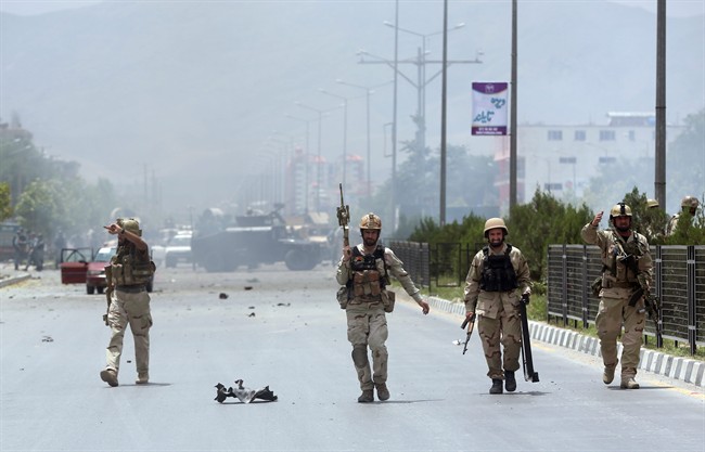 Afghan security forces inspect the site of a suicide attack during clashes with Taliban fighters. 