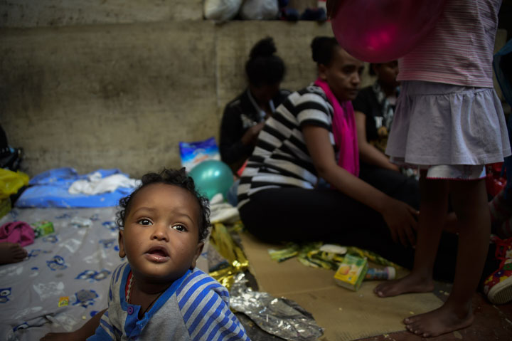 10-month-old Dan from Eritrea waits with his relatives while migrants wait for food at the Milan train station on June 11, 2015, as about 300 migrants, mainly from Eritrea, arrived in Milan late on June 10 and wait to be taken care of by authorities and associations. 