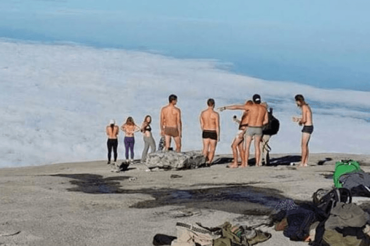 Ten travelers are being blamed for a deadly earthquake because they posed naked on a a sacred mountaintop.