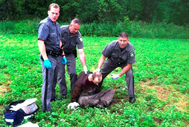 Police stand over David Sweat after he was shot and captured near the Canadian border Sunday, June 28, 2015, in Constable, N.Y. Sweat is the second of two convicted murderers who staged a brazen escape three weeks ago from a maximum-security prison in northern New York. His capture came two days after his escape partner, Richard Matt, was shot and killed by authorities.