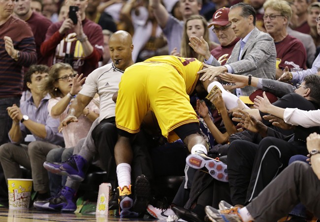 Cleveland Cavaliers forward LeBron James (23) crashes into referee Marc Davis and fans as he goes for a loose ball against the Golden State Warriors during the second half of Game 3 of basketball's NBA Finals in Cleveland, Tuesday, June 9, 2015.