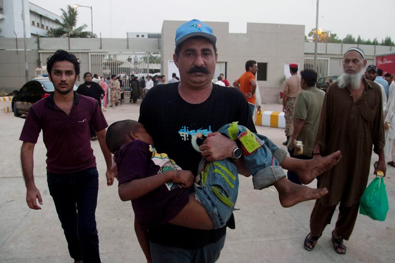 A Pakistani man rushes a child suffering from heatstroke to a hospital in Karachi, Pakistan, Tuesday, June 23, 2015. 