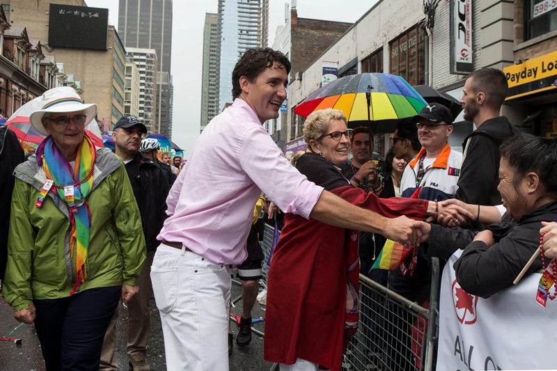 Federal Liberal Leader Justin Trudeau (centre) and Ontario Premier Kathleen Wynne (right) greet the crowd as Wynne’s partner Jane Rounthwaite (left) walks alongside during Toronto’s Pride Parade on Sunday June 28, 2015.