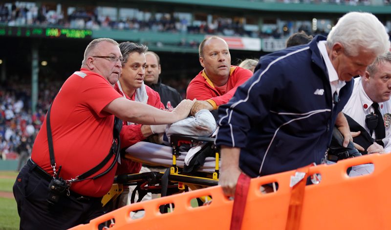 Boston Red Sox medical personnel tend to a woman, who with was hit by a wooden shard, off a broken bat of Oakland Athletics' Brett Lawrie, in the second inning during a baseball game at Fenway Park in Boston, Friday, June 5, 2015. The game stopped as the woman was taken from the stands on a stretcher down the first base line to a waiting ambulance.