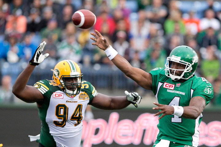 Saskatchewan Roughriders' Darian Durant (4) makes the throw as he is chased by Edmonton Eskimos' Torrey Davis (94) during first half CFL pre-season action in Fort McMurray, Alta., on Saturday June 13, 2015.