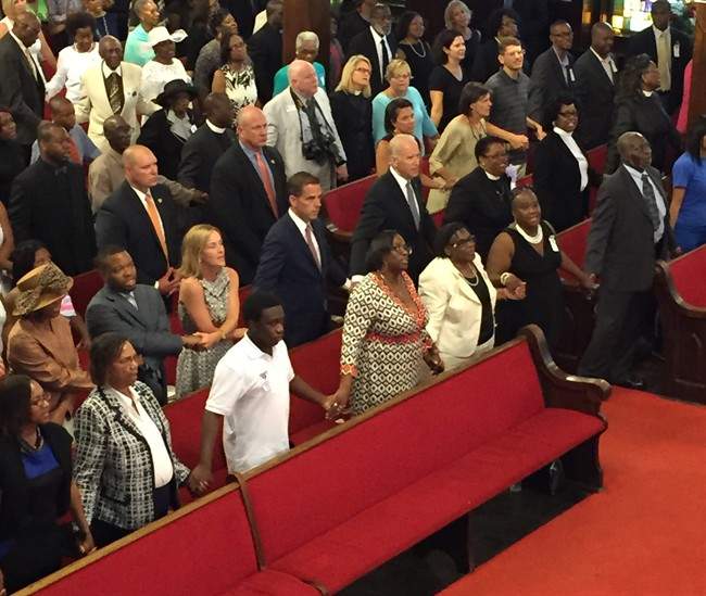 U.S. Vice President Joe Biden, center, with son and daughter-in-law Hunter and Kathleen Biden, to his right, sing “We Shall Overcome” while joining hands with Emanuel AME Church members Sunday, June 28, 2015 in Charleston, S.C. Biden delivered a short speech and said he was there to stand in solidarity with the church and families of the nine people who were killed June 17. (Melissa Boughton/The Post and Courier via AP).