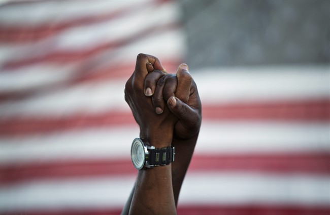People join hands against the backdrop of an American flag as thousands of marchers meet in the middle of Charleston's main bridge in a show of unity after nine black church parishioners were gunned down during a Bible study, Sunday, June 21, 2015, in Charleston, S.C. 