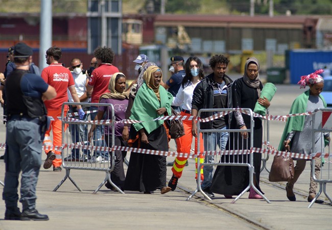 Migrants disembark in the port of Taranto, southern Italy, after being rescued at sea by British ship HMS Bulwark, Monday, June 22, 2015.