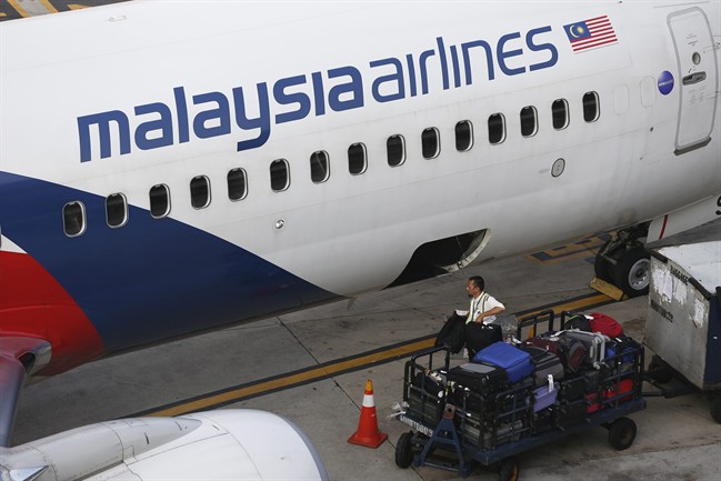 FILE - A Malaysia Airlines ground staff member unloads luggage from a plane at Kuala Lumpur International Airport in Sepang, Malaysia Monday, June 1, 2015. 