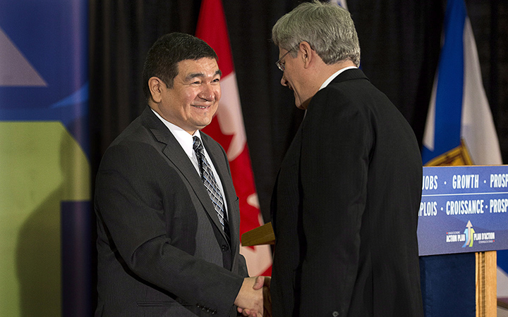 Prime Minister Stephen Harper chats with former federal cabinet minister Peter Penashue, at a news conference in Happy Valley-Goose Bay, Newfoundland and Labrador on Friday, Nov. 30, 2012. 