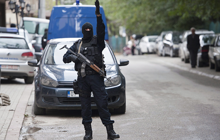 A Kosovo police officer gestures outside the apartment of the vice-president of the radical Islamic political party during a police raid, in Pristina.