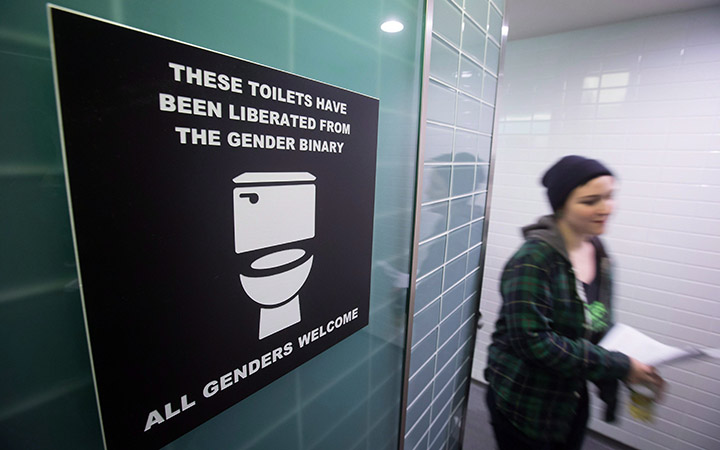 A protester walks out of a altered men's washroom sign at Simon Fraser University on February 18, 2015.
