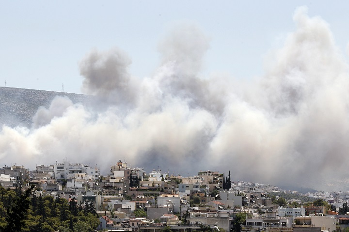 Smoke from a fire travels over the eastern suburbs of Athens on Friday, July 17, 2015. Another fire in Peloponnese, in southern Greece, is burning out of control. The forest fire is being battled by firefighters assisted by water-dropping planes and helicopters, authorities evacuating three villages and the coast guard rescuing scores of people trapped on a beach. (AP Photo/Thanassis Stavrakis).