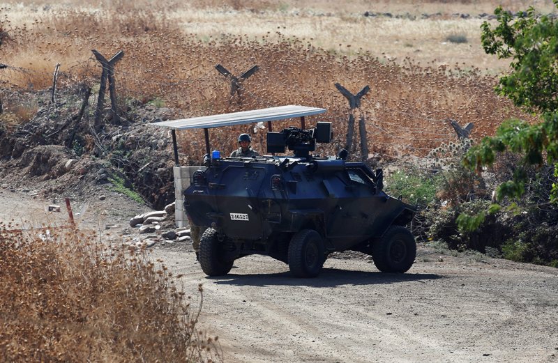 A Turkish soldier stands next to an armoured personnel carrier securing a road near the border with Syria, as seen from the outskirts of the village of Seve, east of the town of Kilis, in southeastern Turkey, Friday, July 24, 2015.