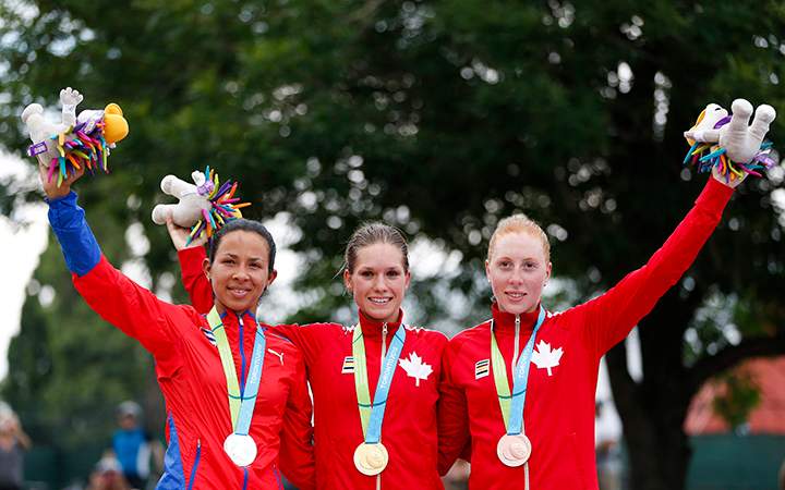 Silver medal winner Marlies Mejia, left, of Cuba, gold medal winner Jasmin Glaesser, center, and bronze medal winner Allison Beveridge, both of Canada, pose to photographers during medal ceremony in the women's road cycling competition at the Pan Am Games in Toronto, Ontario, Saturday, July 25, 2015.