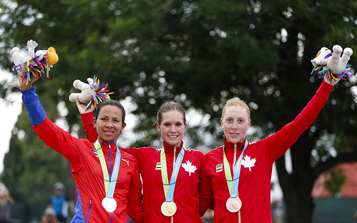 Silver medal winner Marlies Mejia, left, of Cuba, gold medal winner Jasmin Glaesser, center, and bronze medal winner Allison Beveridge, both of Canada, pose to photographers during medal ceremony in the women's road cycling competition at the Pan Am Games in Toronto, Ontario, Saturday, July 25, 2015.