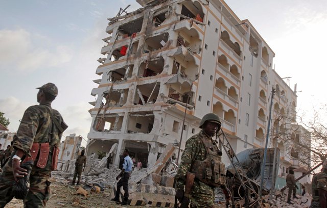 An African Union (AU) soldier walks past the scene of destruction following a suicide car bomb attack in the capital Mogadishu, Somalia Sunday, July 26, 2015.