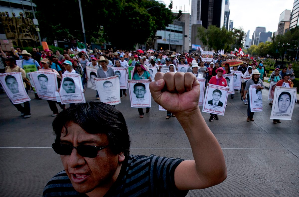 Relatives of the 43 missing students from the Isidro Burgos rural teachers college march holding pictures of their missing loved ones during a protest in Mexico City, Sunday, July 26, 2015.The search for 43 missing college students in the southern state of Guerrero has turned up at least 60 clandestine graves and 129 bodies over the last 10 months.