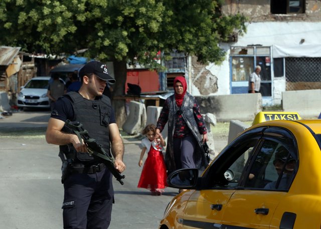A police officer checks IDs as Turkish police raid homes in the Haci Bayram neighborhood of the capital Ankara, Turkey, Monday, July 27, 2015.