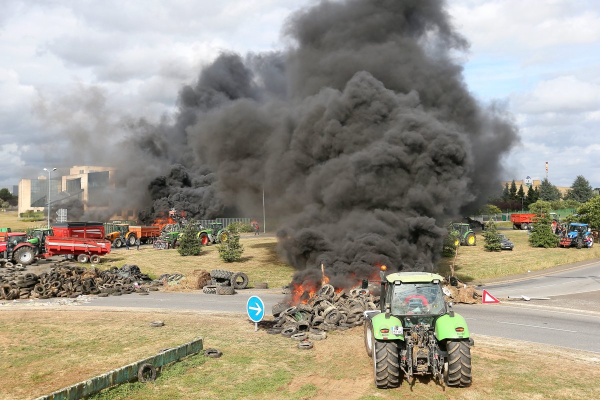 French farmers burn tires as they gather in front of Lactalis' factory, Monday, July 27, 2015, in Laval, western France in order to protest against importation of foreign meat and milk products in France.