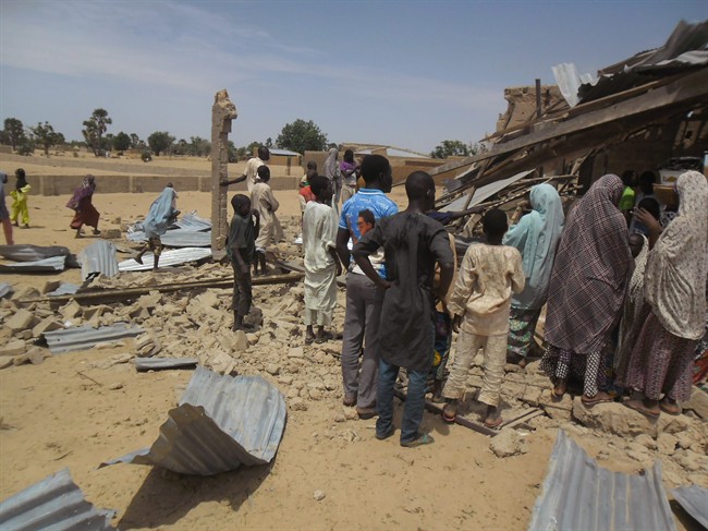 People gather around the Redeemed Christian Church of God, after a bomb blast in Potiskum, Nigeria, Sunday, July 5, 2015. A woman suicide bomber blew up in the midst of a crowded evangelical Christian church service in northeast Nigeria on Sunday and killed at least five people, witnesses said.