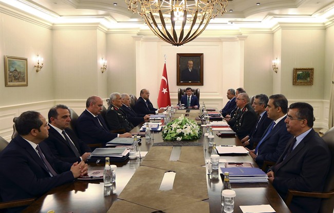 In this Thursday, July 23, 2015 photo, Turkish Prime Minister Ahmet Davutoglu, center, his ministers, military commanders and intelligence officials gather during a security meeting in Ankara, Turkey, hours before Turkish warplanes struck Islamic state group targets across the border in Syria. 