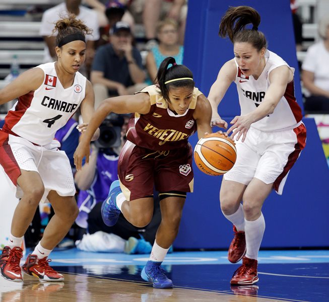 Venezuela's Roselis Silva Serrano, center, breaks away from Canada's Miah Marie Langlois (4) and Kim Gaucher, right, in the first half of a women's preliminary round basketball game at the Pan Am Games Thursday, July 16, 2015, in Toronto. 