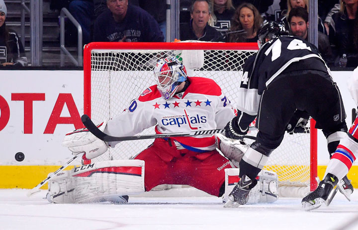 Washington Capitals goalie Braden Holtby, left, deflects a shot by Los Angeles Kings left wing Dwight King during the first period of an NHL hockey game, Saturday, Feb. 14, 2015, in Los Angeles.