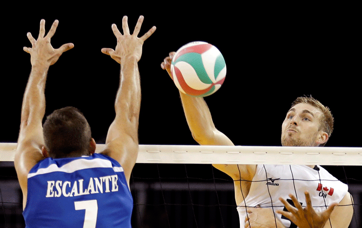 Canada's Rudy Verhoeff hits over the net as Puerto Rico's Enrique Escalante defends during the bronze medal volleyball match at the Pan Am Games Sunday, July 26, 2015, in Toronto. 
