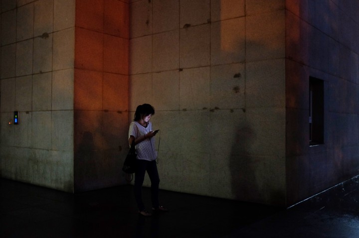 A woman using a smartphone while waiting outside.