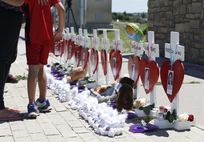 Passers-by move past a row of crosses erected for the 12 victims of the massacre in a nearby movie theatre and to mark the day of the third anniversary of the killing spree, Monday, July 20, 2015, in Aurora, Colo. James Holmes, who had been working toward his Ph.D. in neuroscience, could get the death penalty for the massacre that left 12 people dead and dozens of others wounded early Friday, July 20, 2012.