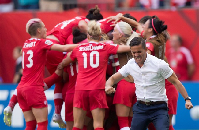Canada coach John Herdman, right, celebrates as Josee Belanger, back, is mobbed by her teammates after scoring against Switzerland during the second half of the FIFA Women's World Cup round of 16 soccer action in Vancouver, B.C., on Sunday, June 21, 2015. As the Women's World Cup wound down, Herdman pointed to his team's very first game when asked about his favourite memories from the tournament.