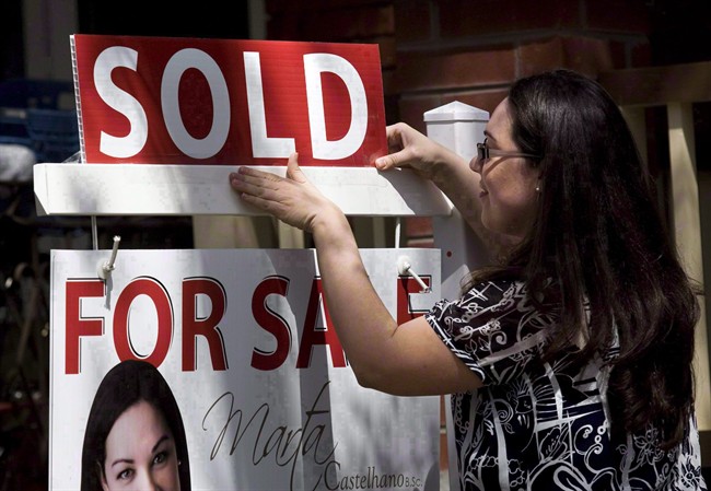 A real estate agent puts up a "sold" sign in front of a house in Toronto Tuesday, April 20, 2010.