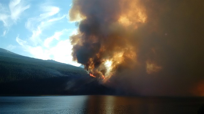 A wildfire rises over a hill in Jasper National Park on Thursday July 9, 2015.