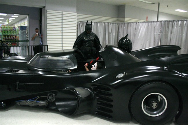 Stephen Lawrence, dressed as batman, stands near his replica Batmobile during a charity appearance at a mall in Kingston, Ontario on Sunday July 26, 2015. Drivers returning from Ontario's cottage country clogged Highway 401 near Napanee on Sunday evening as they watched Batman, in his Batsuit, working on his Batmobile. THE CANADIAN PRESS/HO-Julie Belaire.