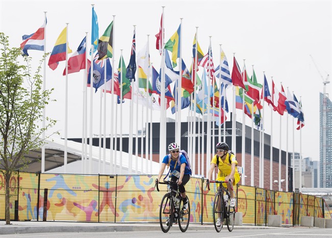 Athletes ride through the athletes' village as the CN Tower stands in the background at the 2015 Pan American Games in Toronto on Thursday, July 9, 2015.