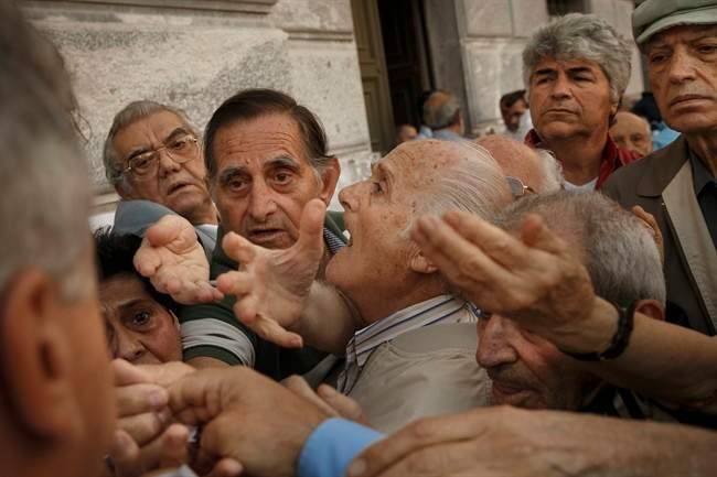 Pensioners try to get a number to enter inside a bank in Athens, Wednesday, July 1, 2015. About 1,000 bank branches around the country were ordered by the government to reopen Wednesday to help desperate pensioners without ATM cards cash up to 120 euros (US $134) from their retirement cheques.