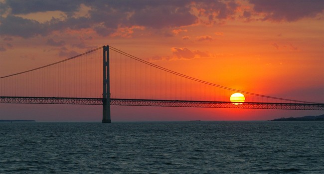 In this May 31, 2002 file photo, the sun sets over the Mackinac Bridge and the Mackinac Straits as seen from Lake Huron. The bridge is the dividing line between Lake Michigan to the west and Lake Huron to the east. 