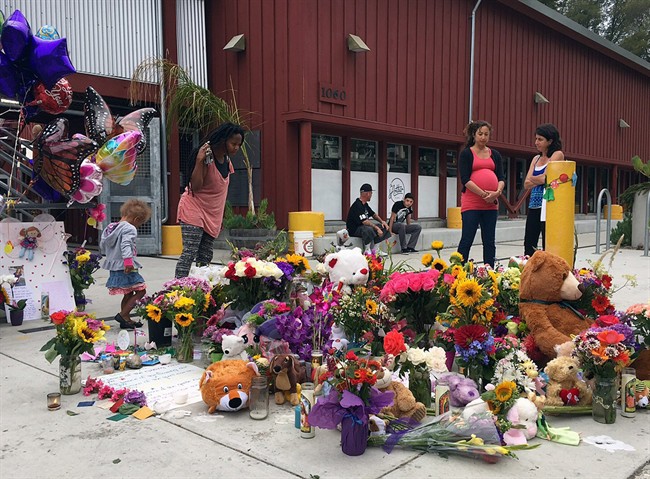 Neighbours look at the growing memorial of flowers, stuffed animals and notes left in memory of Madyson Middleton in Santa Cruz, Calif., Wednesday, July 29, 2015.