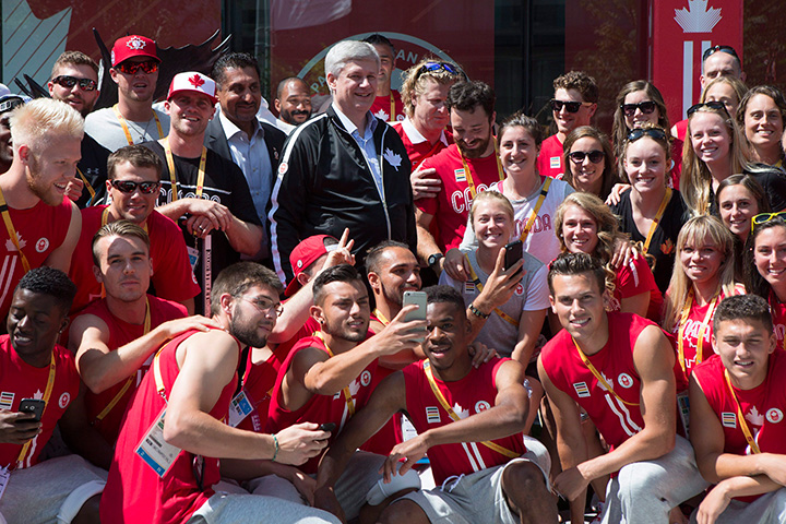 Canadian Prime Minister Stephen Harper poses for a group photo as he visits with Canadian athletes at the 2015 Toronto Pan Am Games athletes' village in Toronto on Friday, July, 10 2015. 