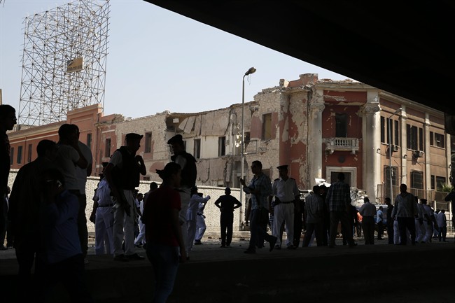 Egyptian policemen stand at the base of the crumbled facade of the Italian consulate following a blast that killed at least one person in Cairo, Egypt, Saturday, July 11, 2015.