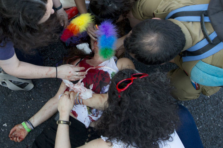 help a wounded woman after an ultra-Orthodox Jew attacked people with a knife during a Gay Pride parade Thursday, July 30, 2015 in central Jerusalem. Israeli police said several people were stabbed.