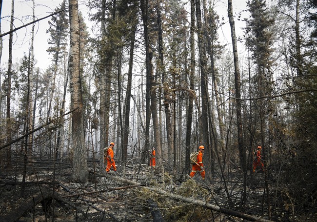Members of the Canadian Forces look hotspots from wildfires near Montreal Lake, Sask., Thursday, July 9, 2015. Rain in some areas will help with suppression, but not enough to change the size or scope of the wildfires.
