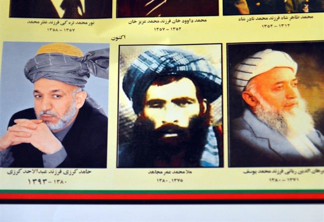 An Afghan shop clerk shows a calendar with pictures of Afghan leaders including Mullah Mohammad Omar, center, in Kandahar, south of Kabul, Afghanistan, Thursday, July 30, 2015. 