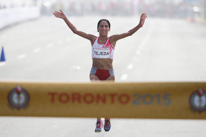 Peru's Gladys Tejeda celebrates before crossing the finish to win the women's marathon at the Pan Am Games in Toronto, Ontario, Saturday, July 18, 2015.