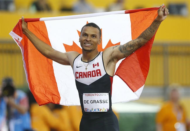Andre De Grasse, of Canada, holds a flag after he wins the gold medal in the men's 100m final during the athletics competition at the 2015 Pan Am Games in Toronto on Wednesday, July 22, 2015. THE CANADIAN PRESS/Mark Blinch.