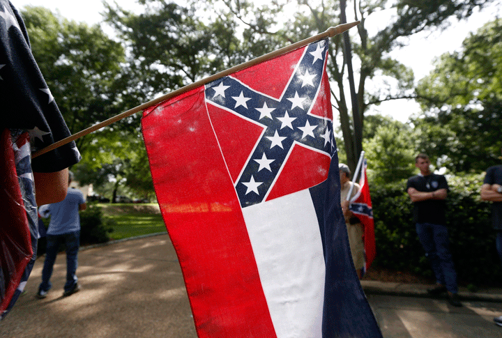A person holds a Mississippi state flag during a rally outside the state capitol, Monday, July 6, 2015, in Jackson, Miss. 