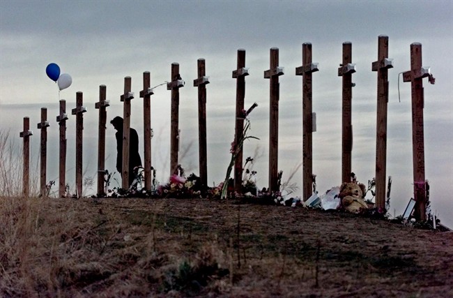 FILE - This April 28, 1999 file photo shows a woman standing among 15 crosses posted on a hill above Columbine High School in Littleton, Colo., in remembrance of the 15 people who died during a school shooting on April 20, 1999. 