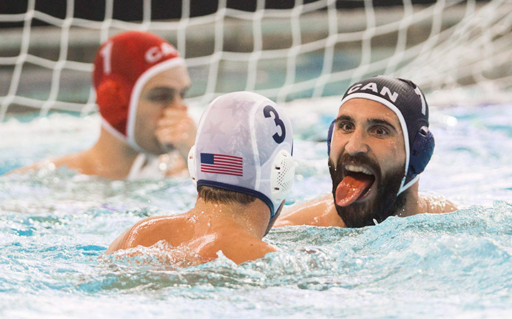 Canada’s George Torakis sticks his tongue out at Alex Obert of the USA, centre, during the men's water polo semi-final match at the Pan Am Games in Markham, Ont. on Monday July 13, 2015. 
